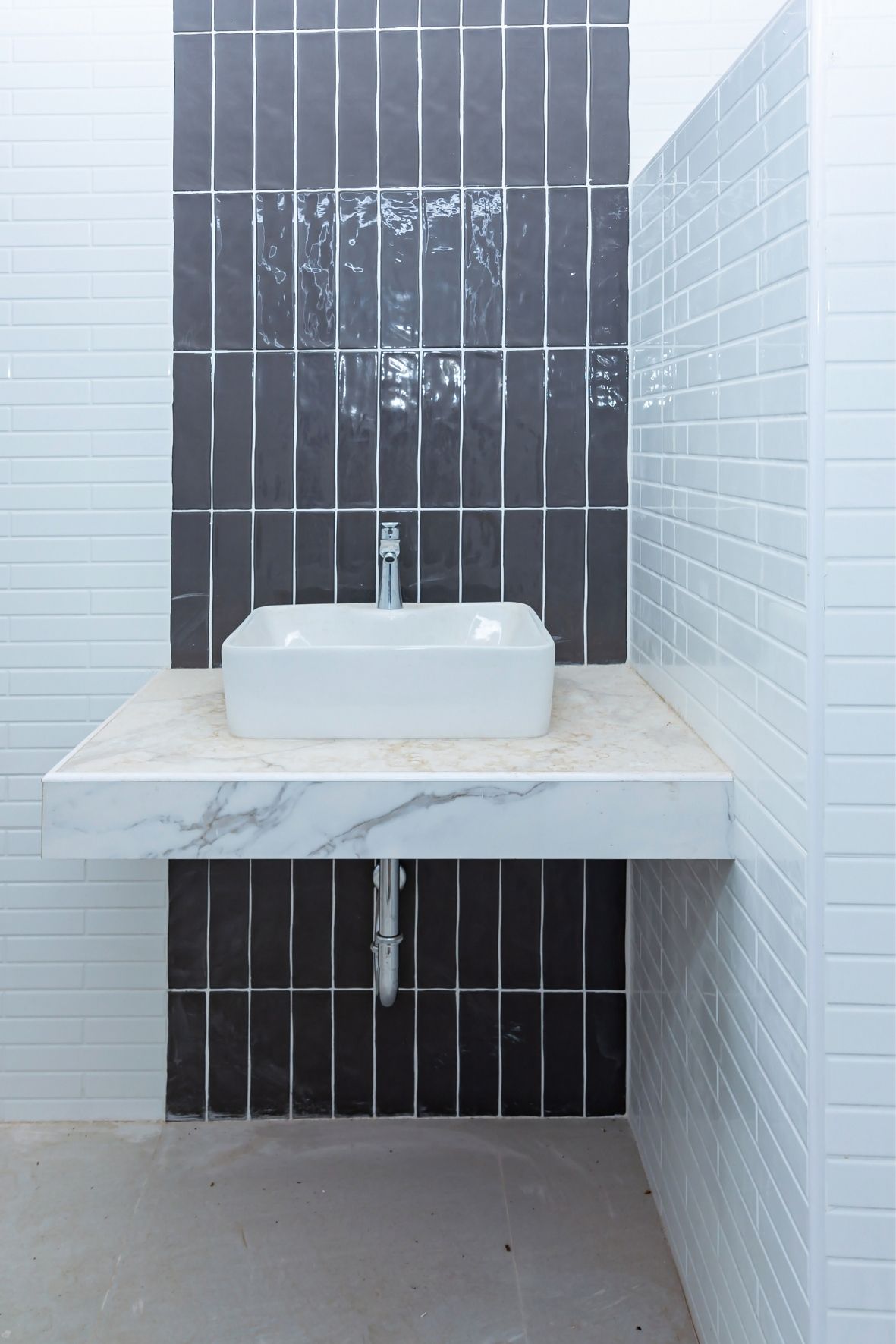 Espace lavabo avec vasque rectangulaire posée sur un comptoir clair et mur carrelé à motifs contrastés à Salaberry-de-Valleyfield